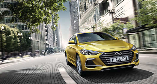 Right side front view of yellow Elantra Sport driving on the street
