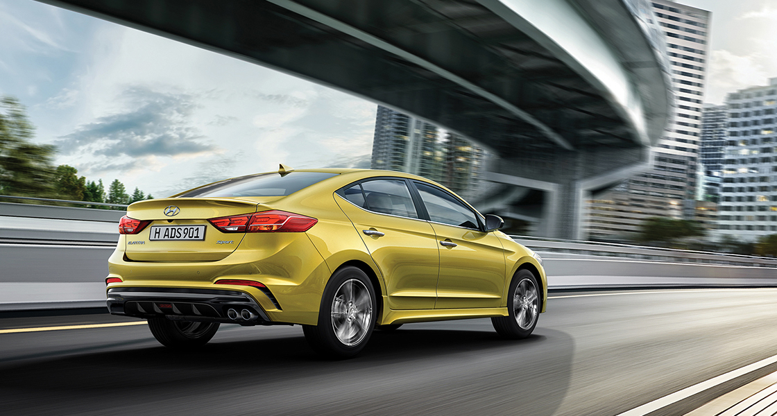 Right side rear view of yellow Elantra Sport driving on the road